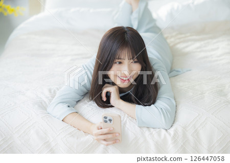 一名婦女在床上的看一個智能手機 一名婦女在床上的看一個智能手機 126447058