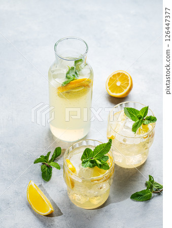 Fresh lemonade with lemon, mint and ice. Two glasses of citrus mojito on a light background 126447377