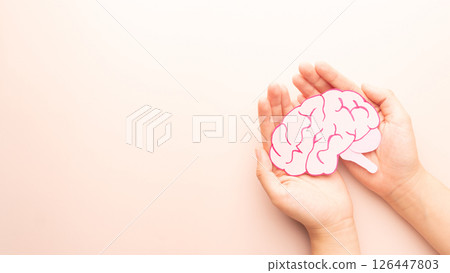 Woman hands holding human brain shape made from paper on beige background. Awareness of Alzheimer, Parkinson's disease, dementia, stroke, seizure or mental health. Neurology and Psychology care. 126447803