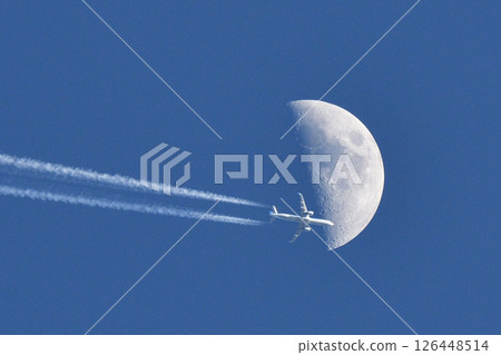 A passenger plane passing through the moon, leaving a contrail 126448514