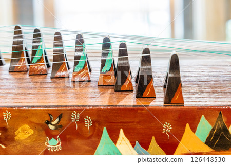 Close-up of the strings on the guqin and the landscape painting 126448530