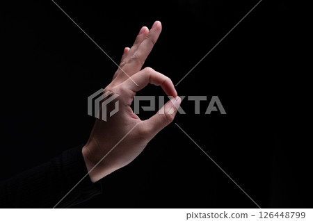 Female hand showing the ok gesture on a black background. Okey hand sign 126448799