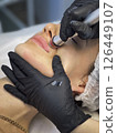 Closeup Of The cosmetologist in medical gloves doing a hydra peeling procedure on the client's cheeks and lips .blurred background 126449107