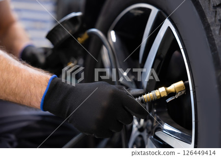 Tire inflation by mechanic in well lit workshop space Tire inflation by mechanic in well lit workshop space 126449414