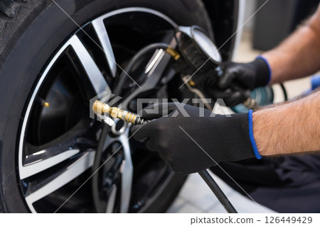 Tire inflation by mechanic in well lit workshop space 126449429