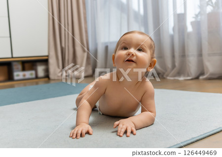 Cute little baby boy crawling on the floor and looking contented Cute little baby boy crawling on the floor and looking contented 126449469