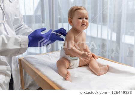 Doctor in sterile gloves doing an injection to a little baby boy 126449528