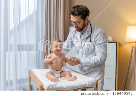 Doctor examining a little baby boy in his office and looking concentrated Doctor examining a little baby boy in his office and looking concentrated 126449542