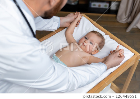 Doctor examining a little baby boy in his office and looking concentrated 126449551