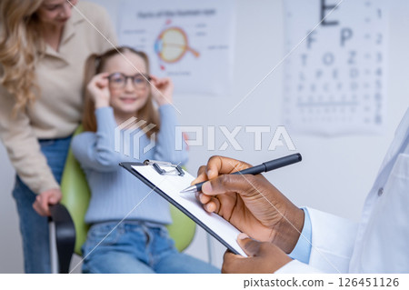 Close up picture of ophthalmologist writing a prescription to a small patient Close up picture of ophthalmologist writing a prescription to a small patient 126451126