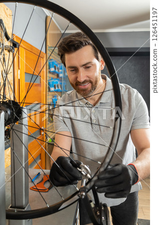 Mechanic in black gloves gripping wheel Mechanic in black gloves gripping wheel 126451197