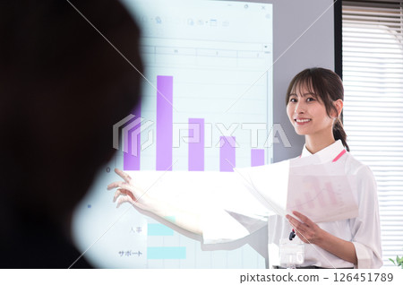 Young woman in casual clothes giving a presentation in front of a screen Young woman in casual clothes giving a presentation in front of a screen 126451789