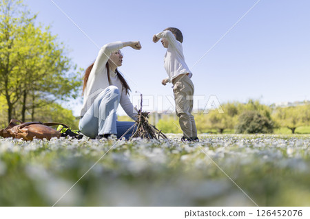 Mother and son building a small bonfire in a field of flowers 126452076
