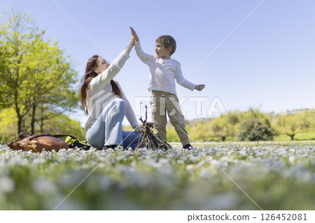Mother and son giving high five in blooming meadow by campfire 126452081