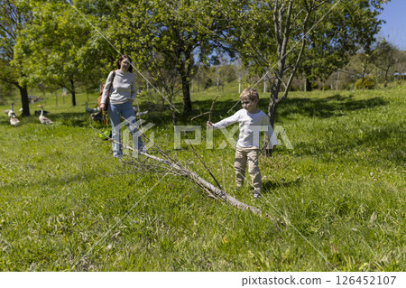 Mother and son walking through orchard with flock of geese 126452107