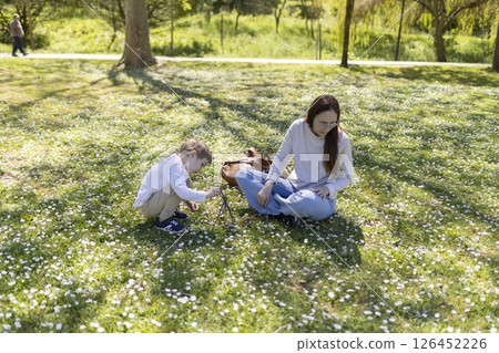 Mother and son relaxing in a field of daisies, enjoying spring day in park 126452226