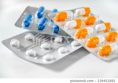 medical orange blue and white pills capsules in blisters, selective focus 126452882