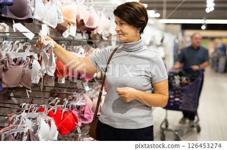 Elderly female customer looking to buy bra in clothes section of supermarket 126453274