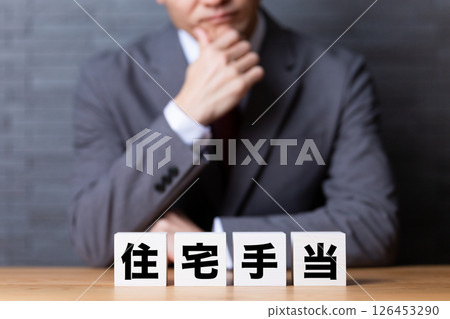 A middle-aged male businessman wearing a suit and worrying about housing allowance blocks 126453290