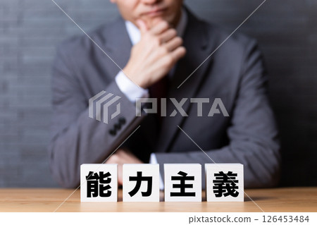 A middle-aged male businessman wearing a suit and worried about the meritocracy block A middle-aged male businessman wearing a suit and worried about the meritocracy block 126453484