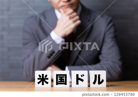 A middle-aged male businessman wearing a suit and a block of US dollars 126453780