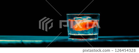 Classic old fashioned cocktail displayed in a rocks glass with a bright orange peel garnish. 126454328