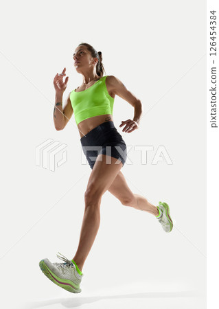 Athletic woman in motion looking forward with determination and balance during sprint. 126454384