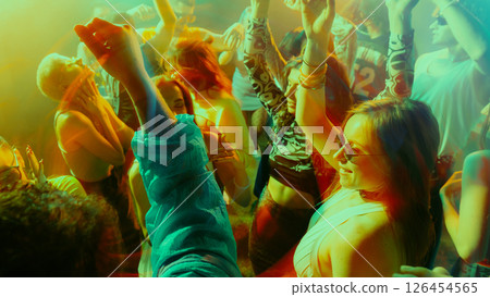 Energetic crowd dancing at a vibrant nightclub with colorful lights. 126454565