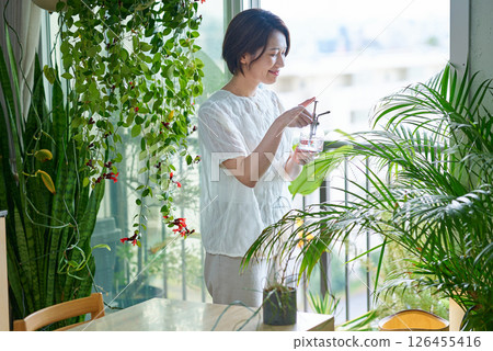 一個女人在房間裡給室內植物澆水 126455416