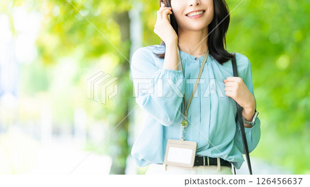 Smiling woman/businesswoman talking on her smartphone while walking along the promenade 126456637