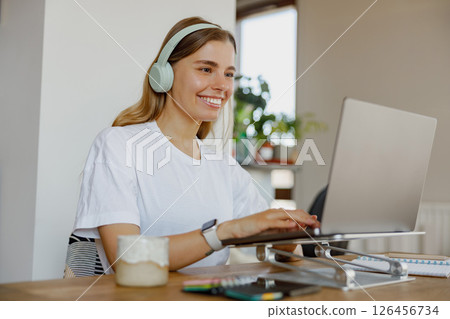 A Young Woman Efficiently Working Remotely While Using Her Laptop and Headphones for Focus 126456734