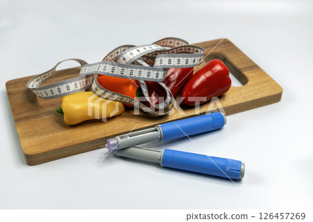 Ozempic Insulin injection pen for diabetics and weight loss and a cutting board with vegetables and a measuring tape. 126457269