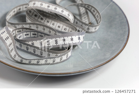 Plate with a measuring tape. Concept of diet and weight loss Plate with a measuring tape. Concept of diet and weight loss 126457271