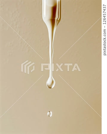 A drop of liquid slowly falling from a dropper against a neutral beige background in a calm and minimalist setting 126457437