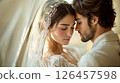 A romantic moment between a bride and groom captured indoors during their wedding celebration in soft, warm lighting 126457598