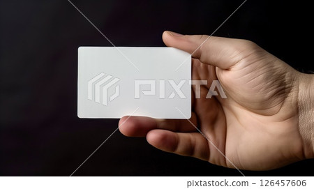 A person holding a blank card with one hand against a dark background in a minimalist setting for emphasis on simplicity and focus A person holding a blank card with one hand against a dark background in a minimalist setting for emphasis on simplicity and focus 126457606