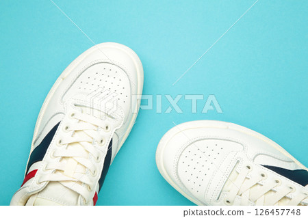 White sneakers, trainers on blue background. Unisex casual sports shoes. Top view. White sneakers, trainers on blue background. Unisex casual sports shoes. Top view. 126457748