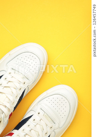 White sneakers, trainers on yellow background. Unisex casual sports shoes. Top view. 126457749