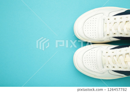 White sneakers, trainers on blue background. Unisex casual sports shoes. Top view. 126457782