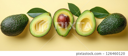 Fresh avocados with vibrant green leaves on a bold yellow background 126460120