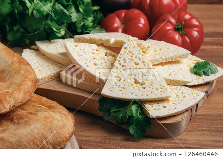Georgian sliced cheese,on a wooden chopping board, with tomatoes with herbs and lavash, rustic style, Georgian cuisine, no people 126460446
