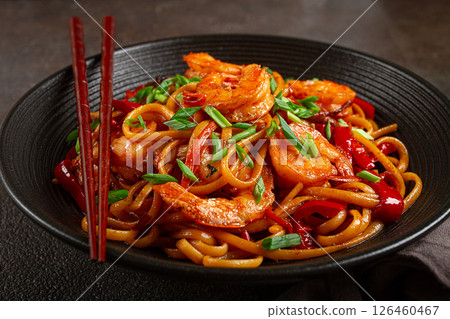 udon stir-fry shrimp noodles with red bell pepper and green onion, served in a black bowl, with chopsticks, dark background, udon stir-fry shrimp noodles with red bell pepper and green onion, served in a black bowl, with chopsticks, dark background, 126460467