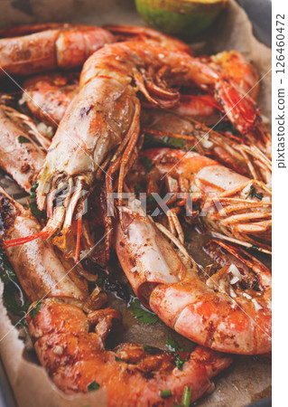 Juicy grilled shrimp, placed on a baking sheet lined with parchment paper, garnished with herbs and lemon. Juicy grilled shrimp, placed on a baking sheet lined with parchment paper, garnished with herbs and lemon. 126460472