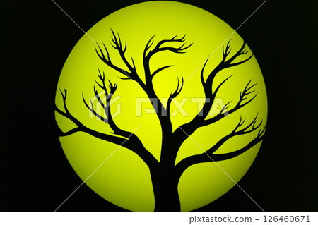 Silhouette of a bare tree against a glowing yellow moon in a dark sky at night 126460671