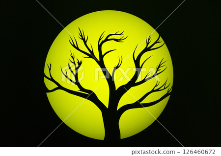 Silhouette of a bare tree against a glowing yellow moon in a dark sky at night 126460672