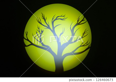 Silhouette of a bare tree against a glowing yellow moon in a dark sky at night 126460673