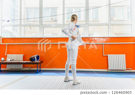 Female fencer putting on protective gear before match indoors. 126460905