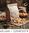 A photography mockup of an empty clean bag with snacks resting on a rustic wooden surface. The high-detail image features bold colors and soft natural lighting, creating a cozy 126461074