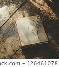 A beautiful invitation card mockup held over a rustic wooden table. Natural light and soft shadows create warm tones, giving an intimate and charming atmosphere perfect for events. 126461078