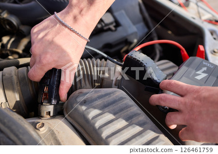 Closeup photo of black car battery connected with jumper cables for repair or recharging Closeup photo of black car battery connected with jumper cables for repair or recharging 126461759